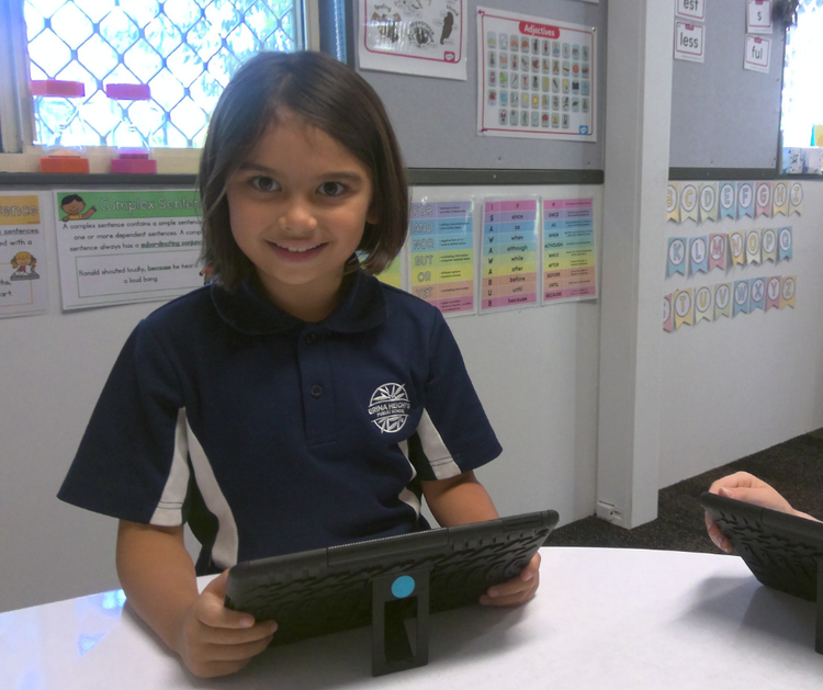 A smiling, young girl working on an ipad during learning support tuition