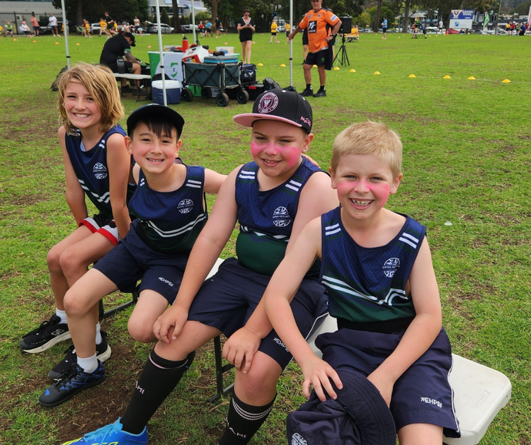 Four happy, young students sitting on a bench after a fun footy game