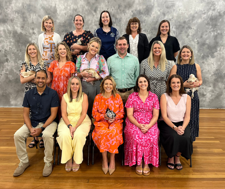 A group picture of staff who are smiling and holding the school chickens