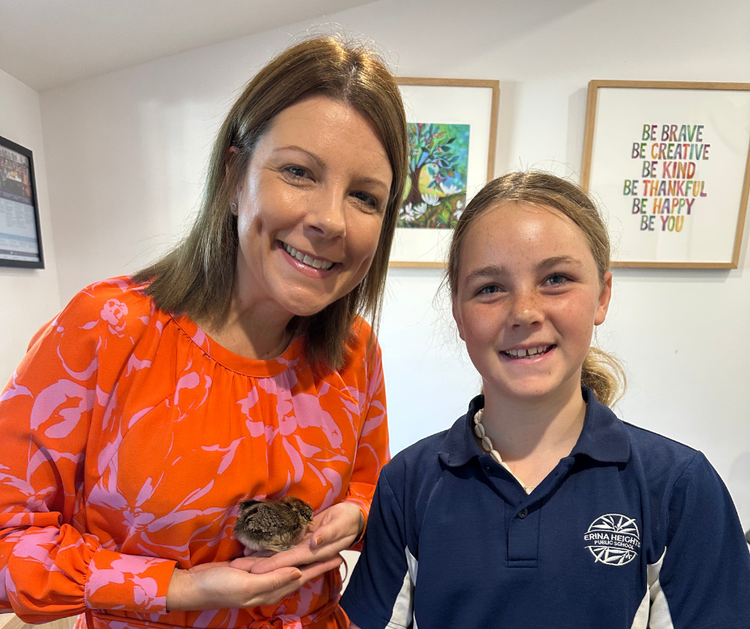 Renee, our principal, holds a baby chick and smiles happily with a happy, young, female student